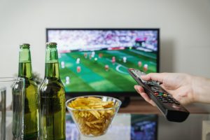 someone holding a remote watching sports